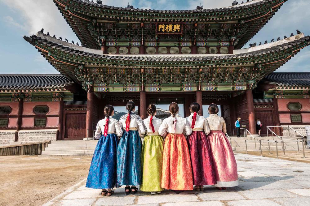 Nếu ở Việt Nam, áo dài là Quốc phục thì tại Hàn Quốc, Hanbok chính là trang phục truyền thống Hàn Quốc của họ. Hầu như bất kỳ ai cũng đều có cho riêng mình một bộ Hanbok. Ra đời trong thời đại Joseon, hiện nay Hanbok chủ yếu được mặc nhiều hơn thường phục trong các dịp lễ tết, hội hè, ngày cúng giỗ, tang lễ. Cùng Korea Link hiểu rõ hơn về bộ trang phục này nhé!   Ý nghĩa của áo Hanbok Hanbok Hàn Quốc đều được người dân mỗi nước thường xuyên sử dụng trong các dịp lễ tết. Bởi vào những dịp ngày tết ngày hội cổ truyền như vậy, mặc trang phục  truyền thống để thể hiện tấm lòng của con cháu luôn nhớ tới tổ tiên cội nguồn. Hanbok toát lên vẻ đẹp kín đáo, elệ của phái đẹp xứ Hàn và nét đứng đắn của phái nam. Hanbok được thiết kế nhiều lớp và kín đáo như vậy cũng là để phản ánh tư tưởng của người Hàn chịu sự ảnh hưởng sâu sắc của Nho giáo mà tuân theo lễ nghĩa nghiêm ngặt, trong đó bao gồm cả việc ăn mặc nữa.  Vì là trang phục truyền thống Hàn Quốc nên Hanbok Hàn Quốc phản ánh những nét đặc trưng của văn hóa Hàn Quốc. Hanbok có hai lớp là để thích nghi với khí hậu lạnh và khô. Màu sắc và hoa văn của Hanbok đặc biệt phong phú, mỗi màu sắc và hoa văn lại ẩn chứa một  ý nghĩa nhất định, nhưng có thể khái quát lên rằng đó chính là mong muốn hòa nhập với thiên nhiên, có được một cuộc sống ấm no hạnh phúc và ước muốn chung sống với nhau một cách hòa bình giữa các quốc gia.  Hanbok đã trải qua nhiều giai đoạn biến đổi, và đến ngày nay cũng đều được cách tân để phù hợp với nhu cầu và yêu cầu của người mặc. Hanbok cách tân không những vẫn lưu giữ được những nét đẹp truyền thống đặc trưng của dân tộc mà còn trở nên tiện dụng hơn trong cuộc sống hằng ngày, hơn thế nữa còn góp phần quảng bá hình ảnh của đất nước đến với bạn bè thế giới thông qua chính vẻ đẹp sự cách tân của bản thân bộ trang phục.  Cách mặc áo Hanbok​ Với nữ khi mặc Hanbok lót màu trắng là mặc váy trước, cố định váy bằng dây buộc hoặc như Hanbok hiện nay có sẵn chun bao quanh, phần chun cao đến che quá ngực nên có thể mặc thêm jeogori lót hoặc không. Sau đó lớp Hanbok chính bên ngoài cũng mặc tương tự, phần quan trọng là thắt nơ goreum sao cho đẹp. Goreum cần được thắt về bên tay phải người mặc, độ rủ mềm mại vừa phải để giữ được nét nữ tính và thanh lịch của phái nữ. Vải của bộ áo không được để nhàu và chima phải giữ được nếp và độ phồng ban đầu.  Với nam cũng là mặc baji lót màu trắng trước, sau đó đến jeogori, dáng áo mở có dây cùng chất liệu buộc lại. Sau đó mặc baji ngoài rồi đến áo khoác. Nếu là durumagi  thì chỉ cần khoác vào và buộc bằng dalleyong là xong. Dalleyong có thể là một sợi dây mảnh đeo thêm miếng ngọc bội hoặc móc treo thắt nút bằng vải để trang trí, hoặc có thể là một thắt lưng vải bản to để cố định áo. Nếu là áo khoác cộc tay (cùng kiểu với jeogori) thì mặc tương tự như jeogori, dây buộc áo khoác này cũng là vải cùng chất liệu nhưng được thắt chặt và rủ về bên tay phải.  Đặc điểm của Hanbok Hàn Quốc trong cuộc sống hiện đại Thời xưa khi tình trạng phân chia giai cấp còn nặng nề thì ở Hàn Quốc, chất liệu và màu sắc, hoa văn của trang phục chính là căn cứ phân biệt tầng lớp xã hội. Các nhà thiết kế cũng đã biến đổi chất liệu, kết cấu, kiểu dáng và màu sắc rất nhiều để làm phong phú thêm sự lựa chọn cho khách hàng. Áo Hanbok Hàn Quốc đến giờ vẫn giữ nguyên được những nét đẹp đặc trưng, những ý nghĩa tiềm ẩn sâu xa mà lại được cách tân để có thêm nhiều đặc điểm phù hợp hơn với cuộc sống hiện đại. Không còn chuyện người có tiền mới có thể mặc trang phục sặc sỡ, làm từ lụa, tơ tằm hay các loại vải cao cấp nữa.    Ở thời hiện đại, bất cứ ai cũng có thể mặc trang phục truyền thống bằng chất liệu bất kì với màu sắc, hoa văn nào mà mình mong muốn. Điều quan trọng hơn cả là Hanbok đã trải qua cuộc cách mạng cách tân rất độc đáo để phục vụ tối đa nhu cầu của người dân, để trang phục truyền thống có thể trở thành một phần thường trực trong cuộc sống của người dân hiện đại.
